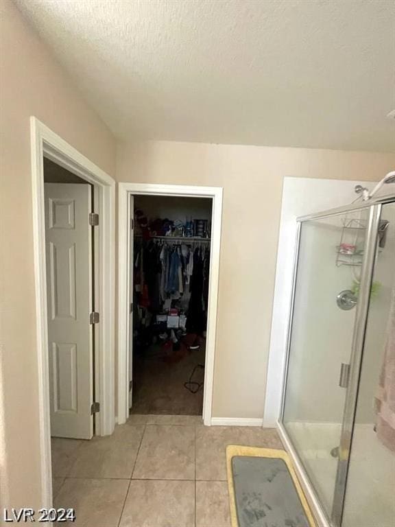 bathroom featuring a textured ceiling, a shower with door, and tile patterned flooring