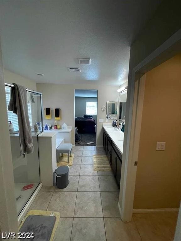 bathroom featuring vanity, a shower with door, tile patterned floors, and a textured ceiling