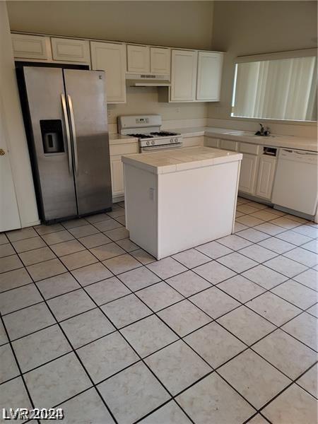 kitchen with light tile patterned floors, white appliances, and white cabinetry