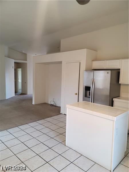 kitchen with white cabinets, stainless steel fridge with ice dispenser, and light carpet