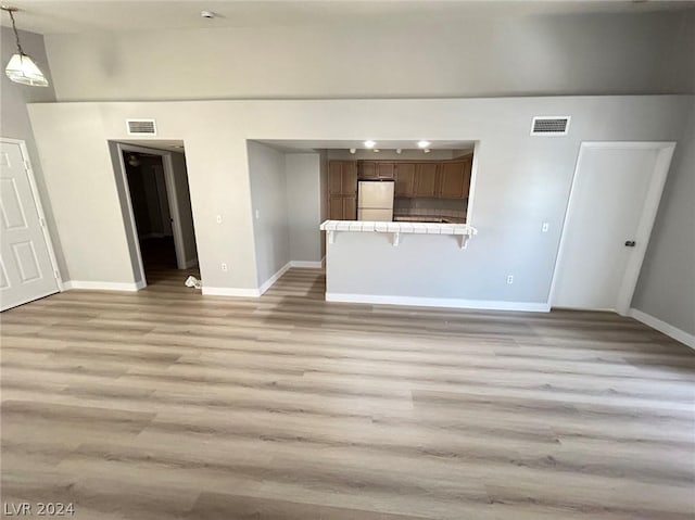 unfurnished living room with visible vents, baseboards, and light wood finished floors