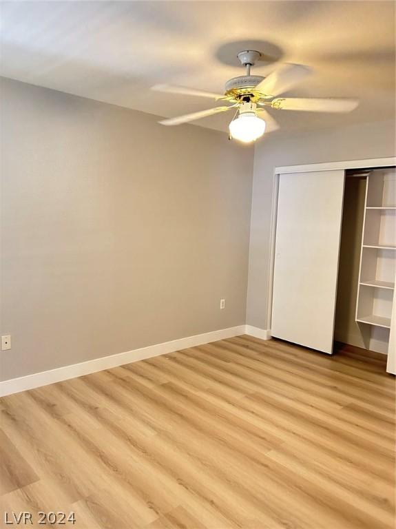 unfurnished bedroom with a ceiling fan, baseboards, a closet, and light wood-type flooring