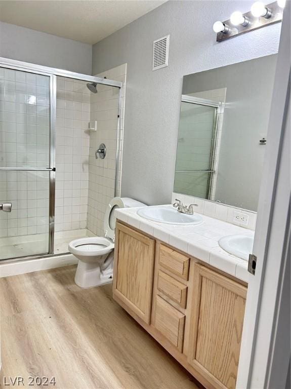 bathroom featuring visible vents, a shower stall, toilet, wood finished floors, and a sink