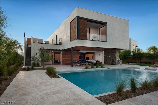 back of house featuring an outdoor living space, a patio area, and a fenced in pool