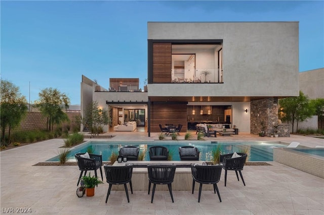 back house at dusk with a fenced in pool, a patio area, and an outdoor hangout area