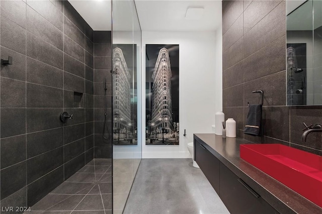 bathroom featuring a tile shower, vanity, and toilet