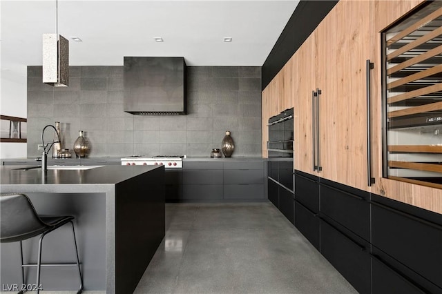 kitchen with a breakfast bar, light brown cabinets, wall chimney exhaust hood, and sink