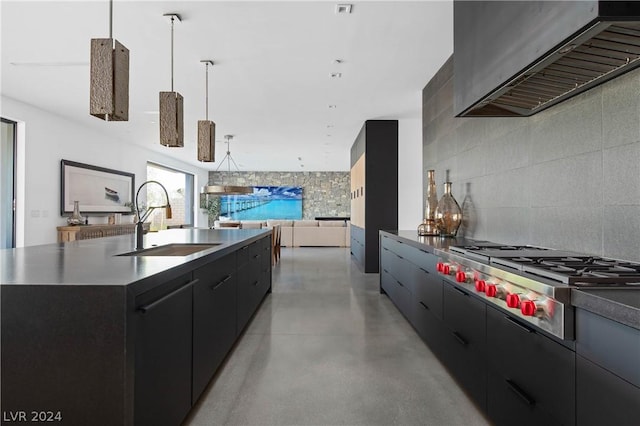 kitchen featuring sink, stainless steel gas cooktop, range hood, a spacious island, and decorative light fixtures