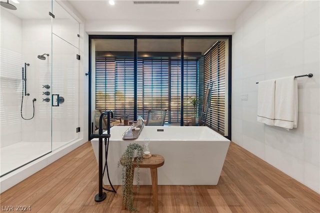 bathroom featuring hardwood / wood-style flooring and plus walk in shower