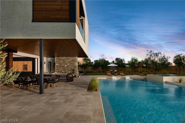 pool at dusk featuring a patio area