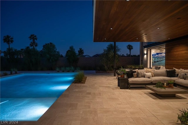 pool at night with an outdoor hangout area and a patio