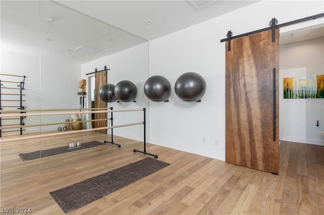 exercise area with a barn door and light hardwood / wood-style floors