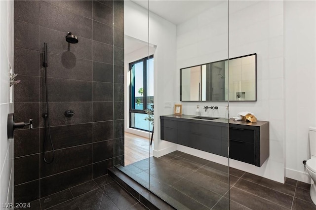 bathroom featuring tile patterned flooring, vanity, toilet, and tiled shower