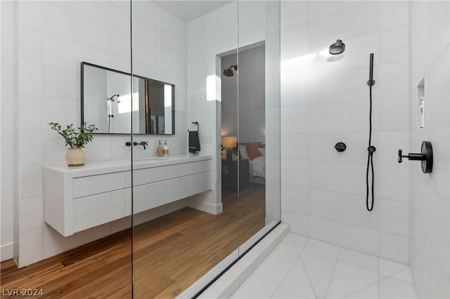 bathroom featuring tile patterned flooring, vanity, and a tile shower