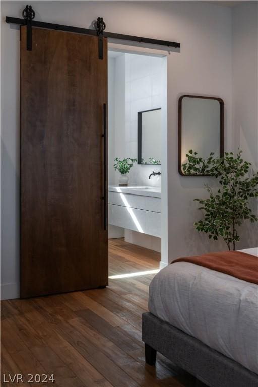 bedroom with a barn door and dark wood-type flooring