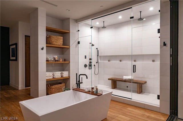 bathroom featuring wood-type flooring and shower with separate bathtub