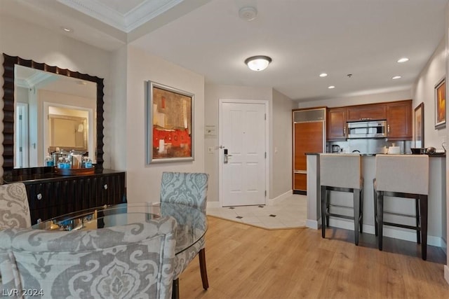 dining area with ornamental molding and light wood-type flooring