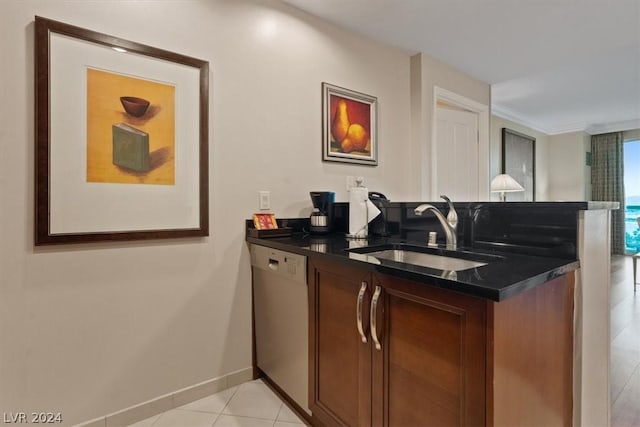 kitchen featuring a sink, dishwashing machine, dark countertops, and light tile patterned floors