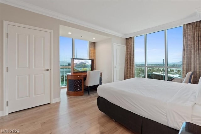 bedroom featuring crown molding, floor to ceiling windows, and light wood-type flooring