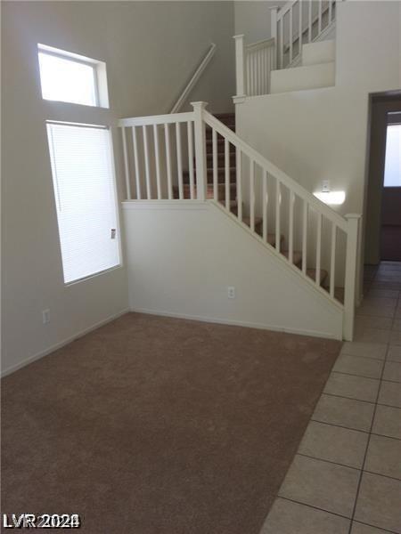 staircase featuring a high ceiling and tile patterned floors