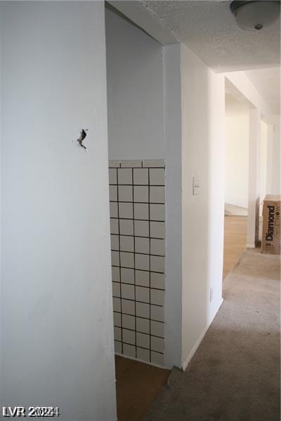 hallway with a textured ceiling and carpet flooring