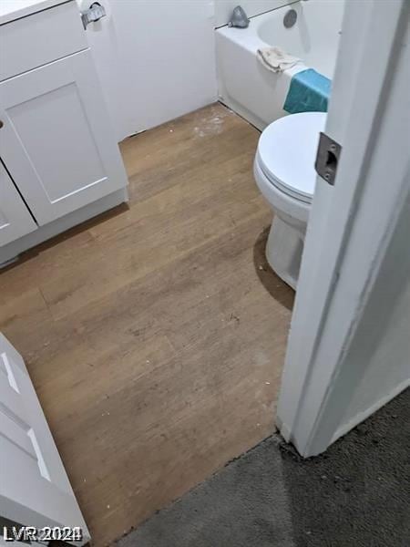 bathroom with toilet, wood-type flooring, and a tub