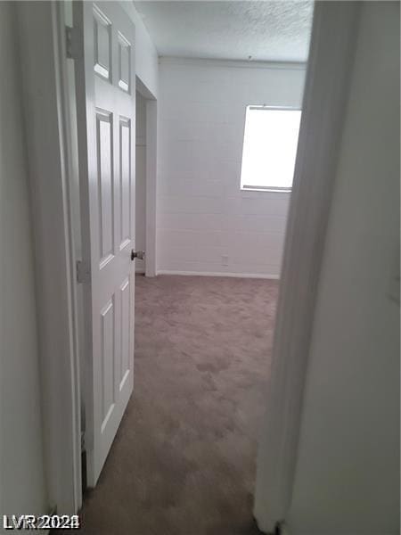 corridor with a textured ceiling and dark colored carpet