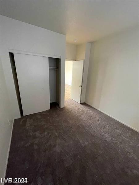 unfurnished bedroom with a closet and dark carpet