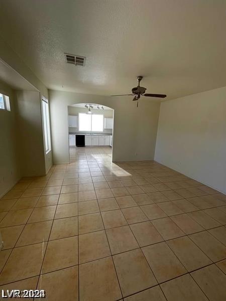 interior space with ceiling fan, a textured ceiling, and light tile patterned flooring