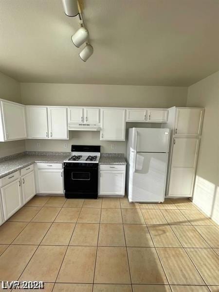 kitchen with light tile patterned floors, white refrigerator, range with gas stovetop, and white cabinetry