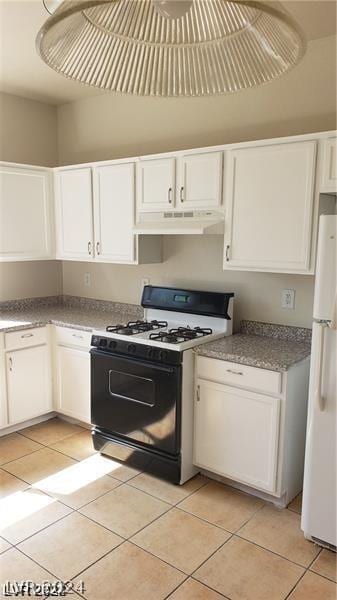 kitchen with light tile patterned floors, range with gas stovetop, white fridge, and white cabinetry