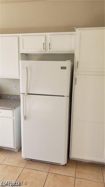 kitchen with white cabinets, light tile patterned floors, and white fridge