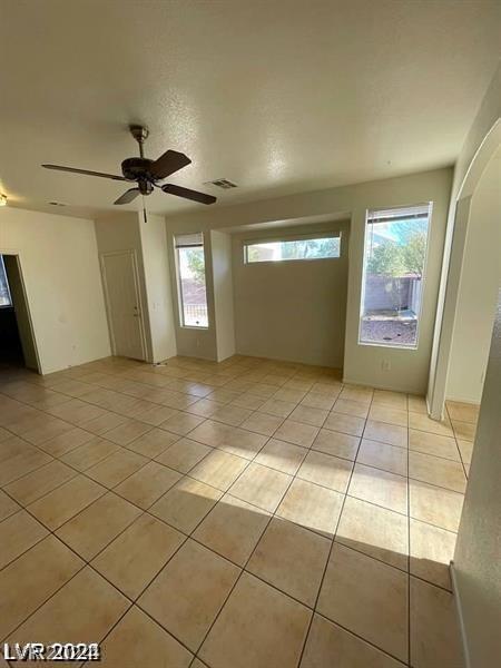 tiled spare room featuring ceiling fan and plenty of natural light