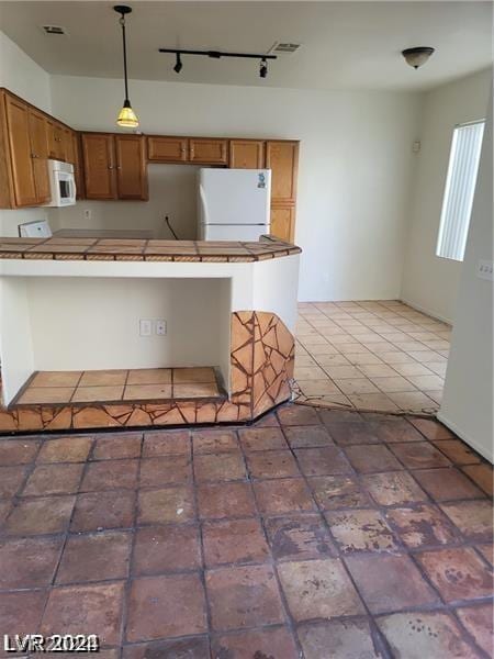 kitchen with hanging light fixtures, a breakfast bar area, white appliances, and kitchen peninsula