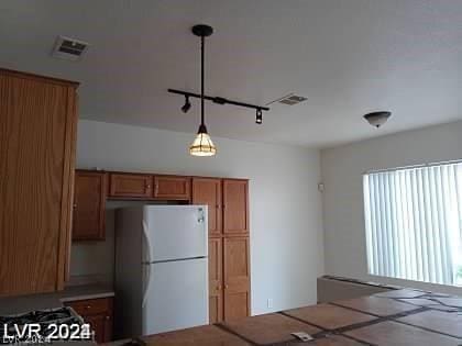 kitchen with pendant lighting, rail lighting, and white refrigerator