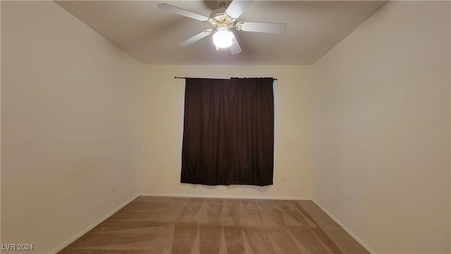 carpeted spare room featuring ceiling fan and baseboards