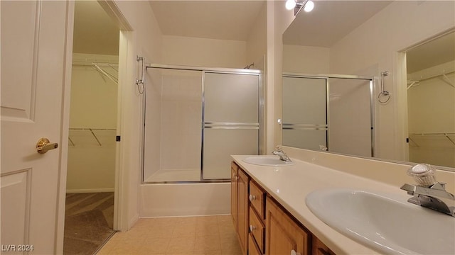 bathroom with double vanity, shower / bath combination with glass door, and a sink