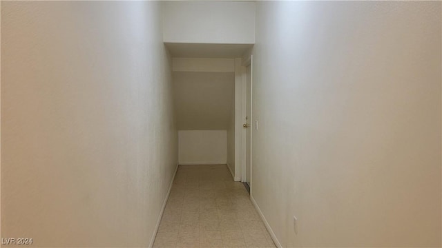 corridor featuring light floors and baseboards