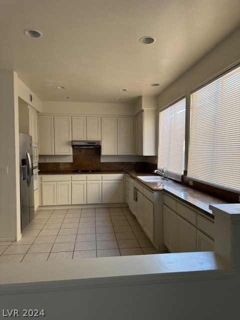 kitchen featuring cooktop, white cabinetry, sink, stainless steel fridge with ice dispenser, and light tile patterned flooring