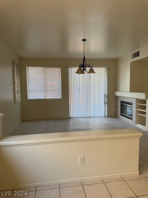 kitchen featuring a notable chandelier, pendant lighting, light tile patterned flooring, and a tile fireplace