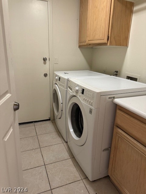 washroom featuring light tile patterned floors, washing machine and clothes dryer, and cabinets