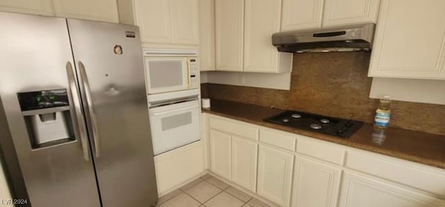 kitchen featuring white appliances, white cabinets, light tile patterned floors, and tasteful backsplash