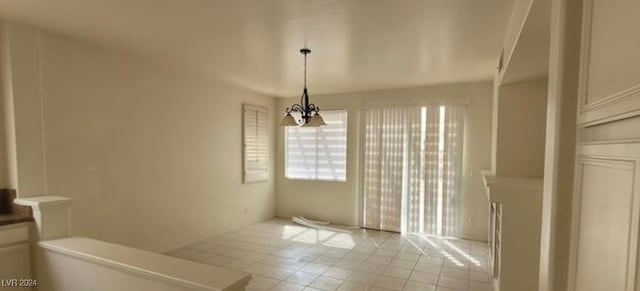 unfurnished dining area with light tile patterned floors and a notable chandelier