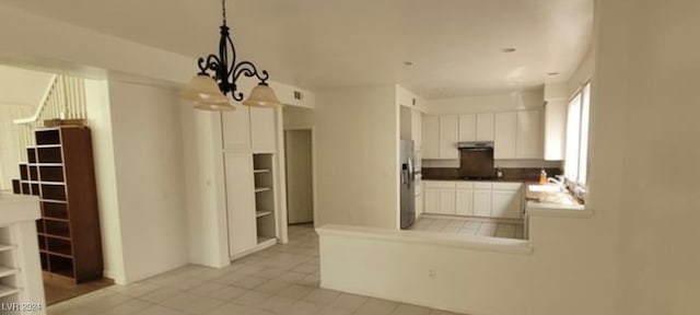 kitchen featuring stainless steel fridge, light tile patterned flooring, a chandelier, and white cabinets