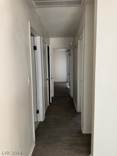 hallway with dark hardwood / wood-style flooring and a textured ceiling