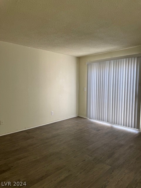 empty room featuring a textured ceiling and dark hardwood / wood-style flooring