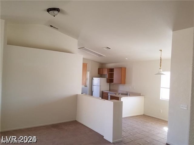 kitchen with lofted ceiling, sink, light tile patterned floors, hanging light fixtures, and white refrigerator