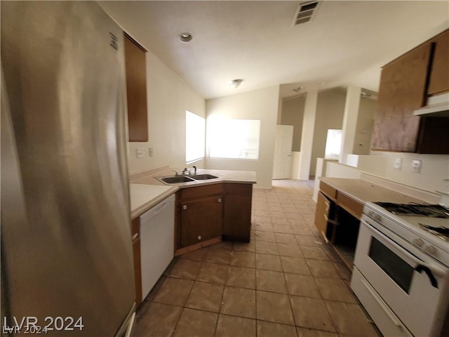 kitchen with light tile patterned flooring, lofted ceiling, sink, and white appliances