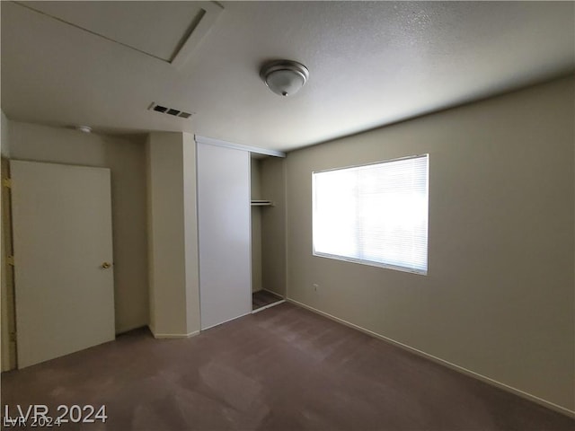 unfurnished bedroom featuring dark carpet and a closet