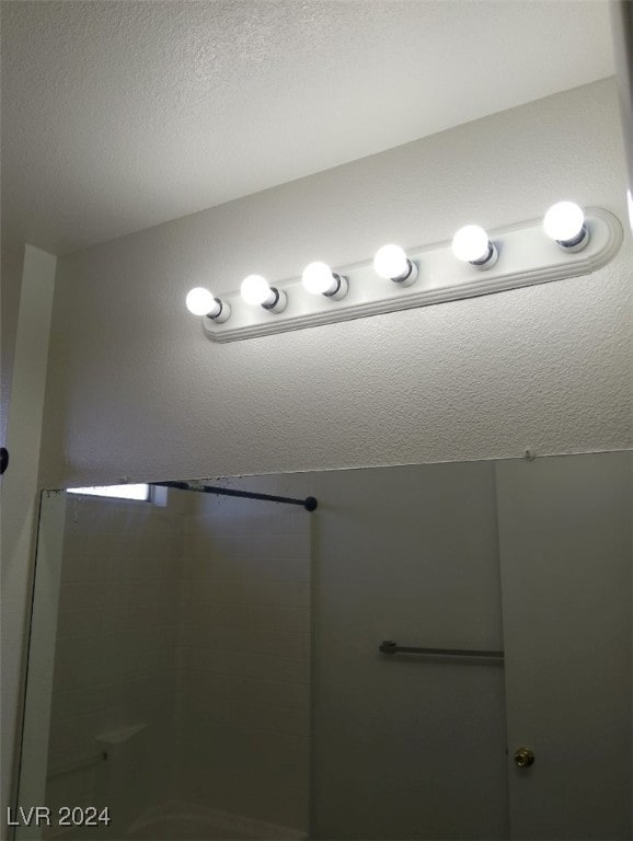 bathroom featuring a shower with door and a textured ceiling